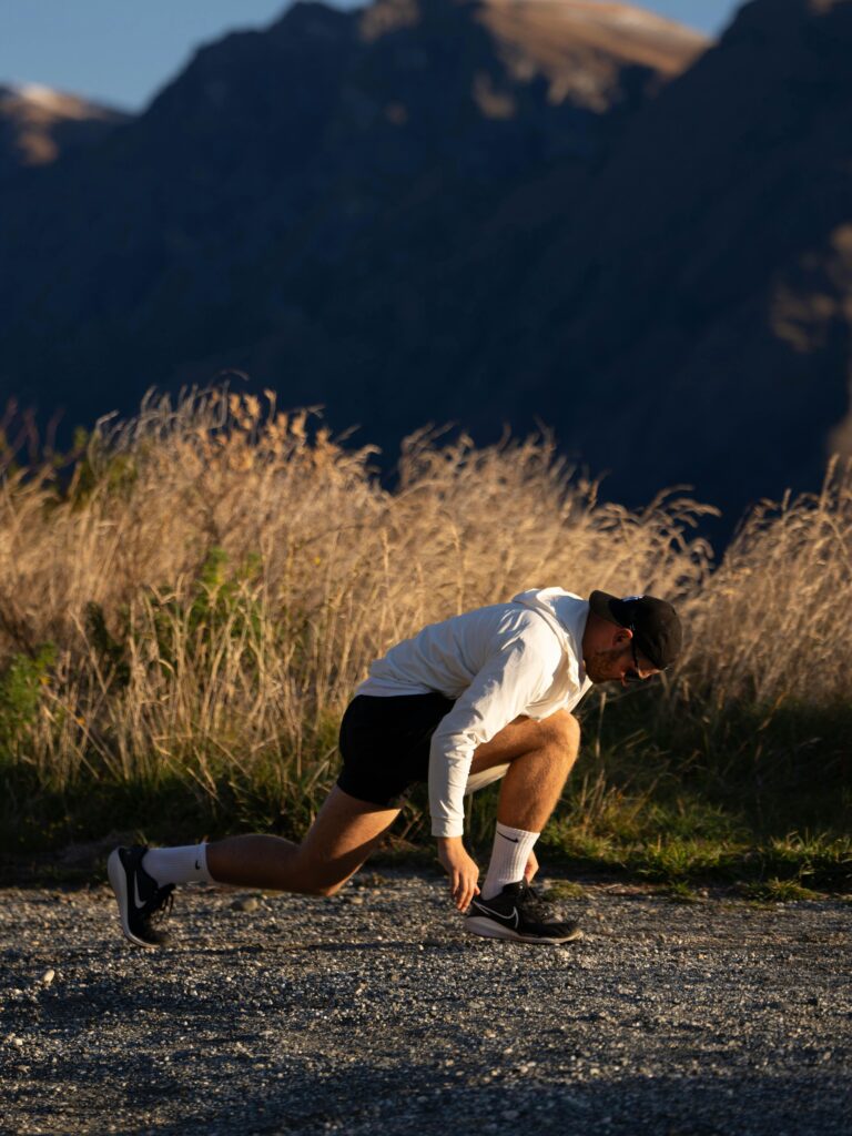 Athlete in sunset light, ready to sprint outdoors in stunning New Zealand landscape.