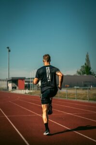 pexels-photo-13159248-13159248 Back view of a fit man running on a sunny outdoor track in Andenne, Belgium.